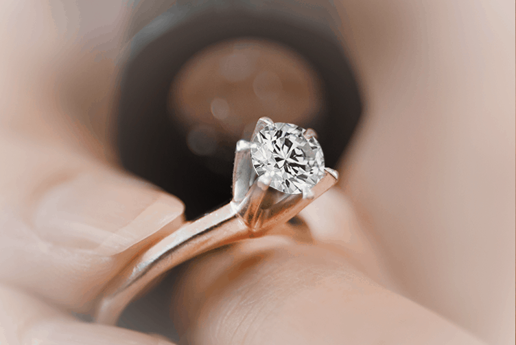 Close-up of a diamond solitaire ring being inspected under magnification, illustrating course modules on the Diamond 4Cs and technical evaluation.