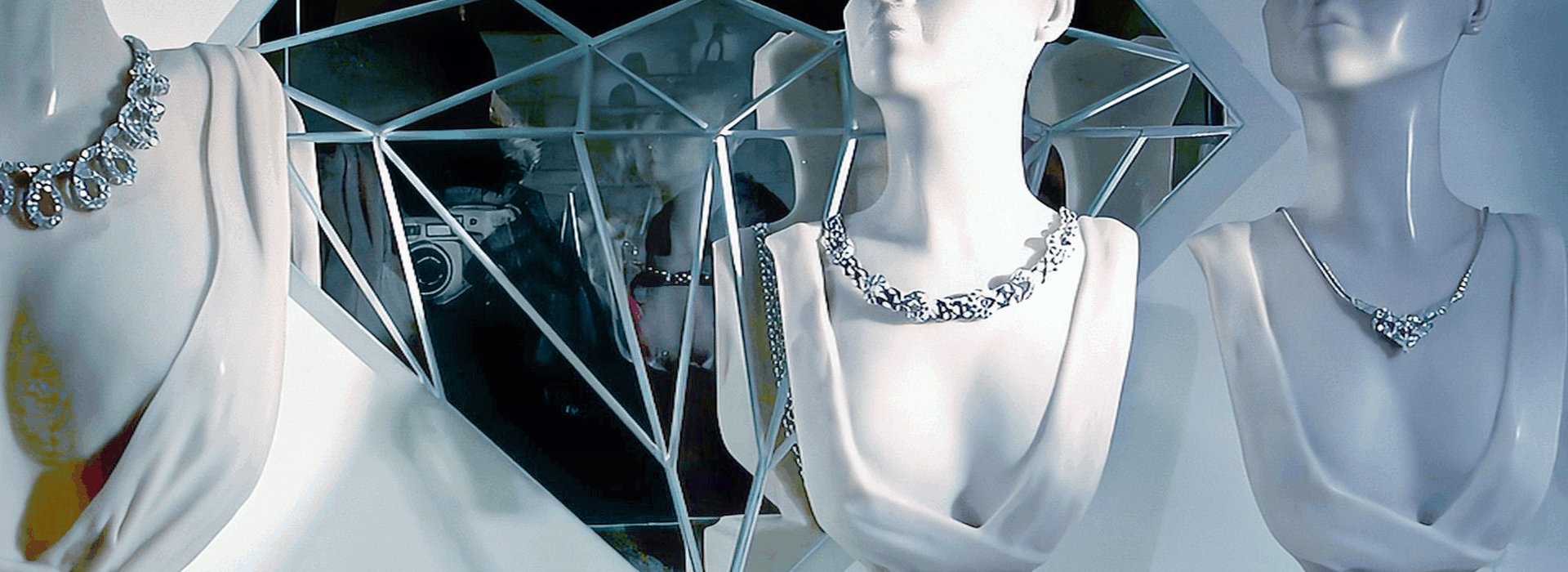 Luxury diamond necklaces displayed on mannequins within a high-end retail showroom environment.