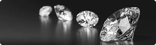 A focused black and white image displaying a row of high-quality, brilliant-cut loose diamonds, reflecting SGL’s commitment to certifying standalone stones.